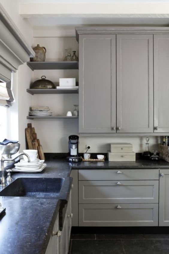 a light grey shaker cabinet kitchen with open shelves, black soapstone countertops and a slight vintage feel