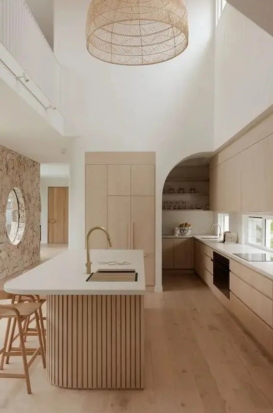a light-stained minimalist kitchen with sleek cabinets, a window backsplash, a curved fluted kitchen island with a curved part and a woven pendant lamp