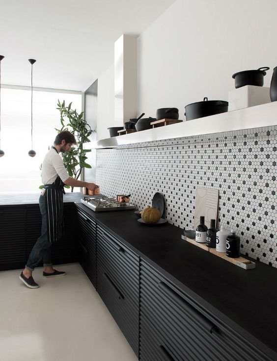 a lovely kitchen with black fluted lower cabinets, black soapstone countertops, a penny tile backsplash and open shelves