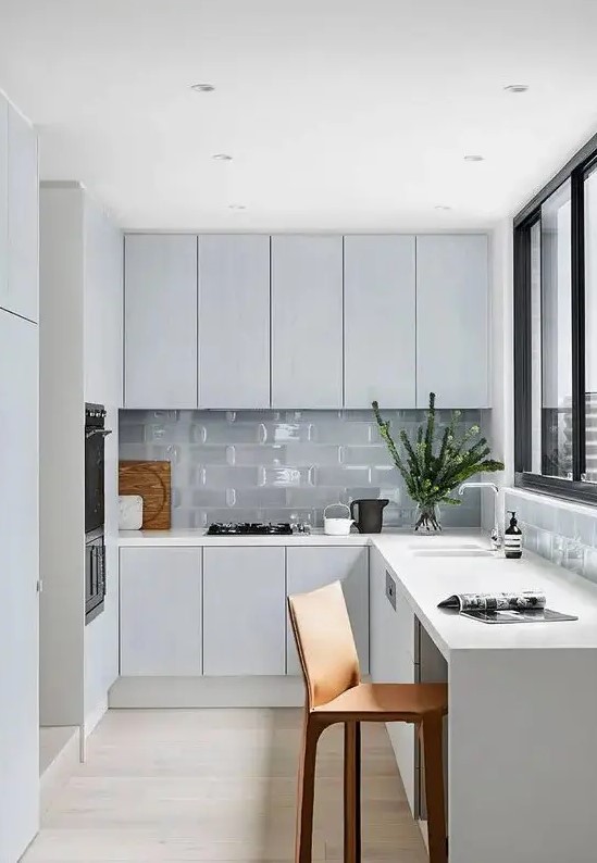 a minimal Nordic L-shaped kitchen with glass tiles and a window with a view is a lovely idea