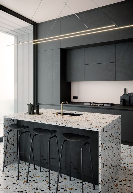 a minimalist black kitchen with sleek no handles cabinets, a gorgeous kitchen island with a terrazzo waterfall countertop and a matching floor