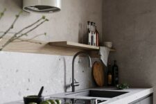 a minimalist graphite grey kitchen with sleek cabinets, light grey countertops, a long blonde wood shelf and a round hood over the cooker