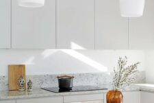 a minimalist grey kitchen with grey terrazzo countertops and white pendant lamps is a chic and welcoming space