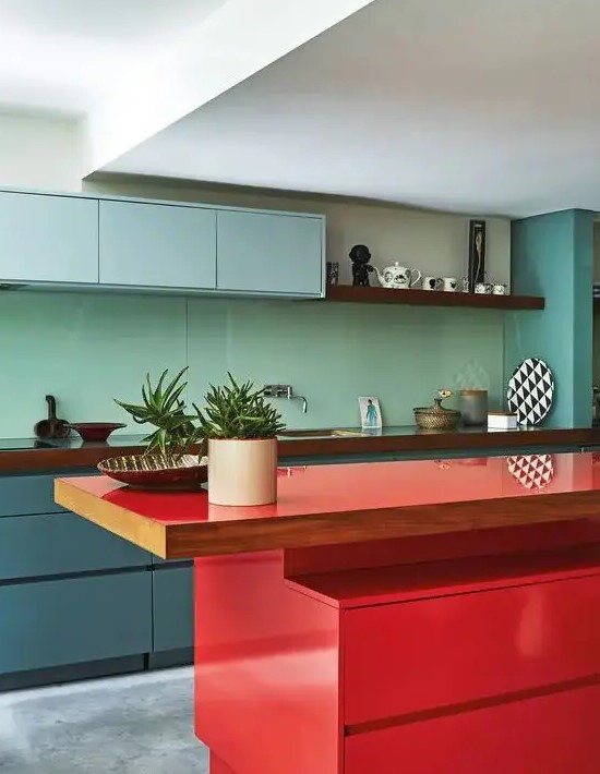 a minimalist kitchen with blue and muted blue cabinets, a mint green backsplash, a bold red kitchen island and wooden countertops
