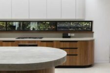 a minimalist kitchen with stained and sleek white curved cabinets, a window backsplash and a curved kitchen island with a stone countertop