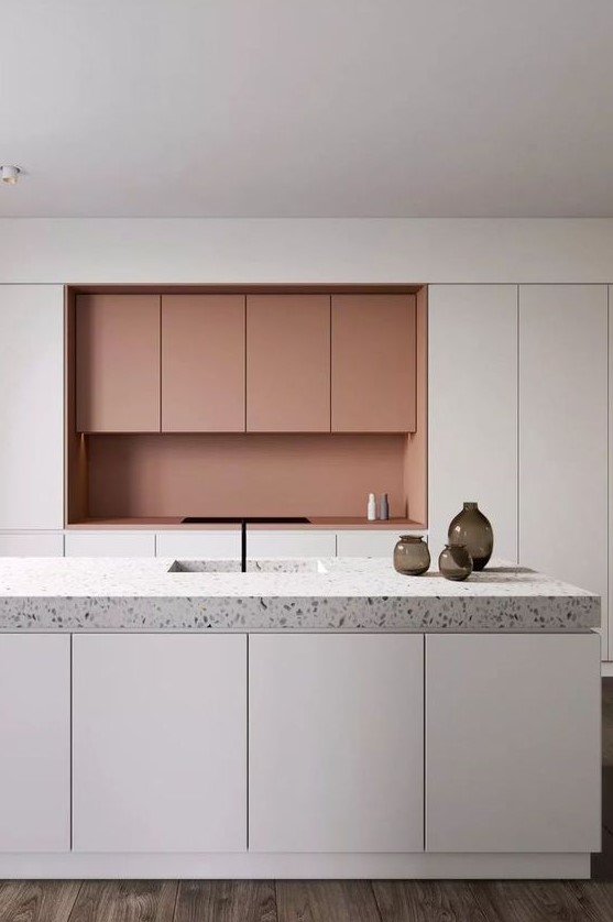 a minimalist white and coral kitchen with no handles and a grey terrazzo countertop that adds pattern to the space