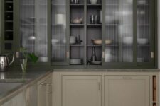 a modern classic greige kitchen with grey stone countertops and dark green fluted glass cabinets with sliding doors
