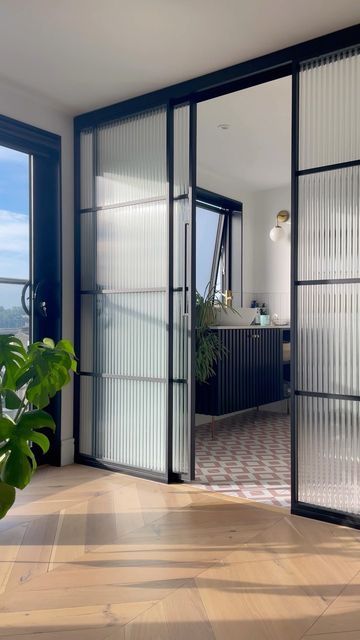 https://www.digsdigs.com/photos/2023/02/a-modern-space-with-fluted-glass-framed-sliding-doors-to-the-bathroom-that-look-airy-and-still-divide-the-space-very-well.jpg