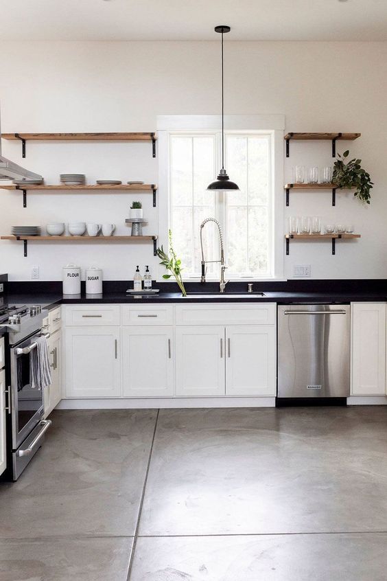 a modern white farmhouse kitchen with shaker cabinets, black soapstone countertops, open shelves instead of cabinets