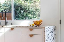a modern white kitchen with flat panel cabinets, a black and white waterfall terrazzo countertop and black fixtures