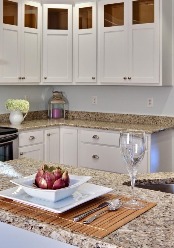 a modern white kitchen with shaker cabinets, greige granite countertops that raise to the walls as a backsplash