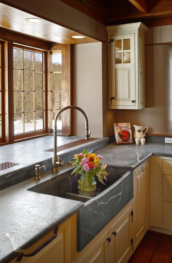 a neutral farmhouse kitchen with shaker cabinets, black soapstone countertops and a bay window is adorable