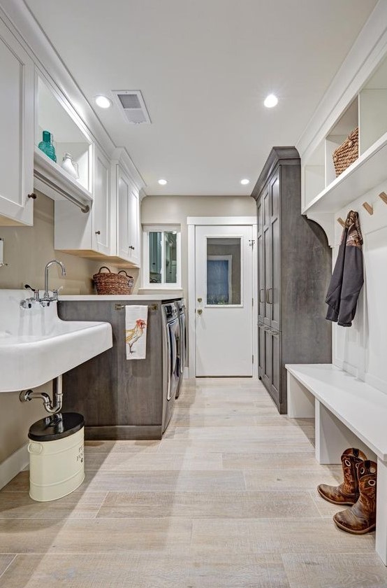 a neutral farmhouse mudroom laundry space with white and grey cabinetry, with shaker panels and an open storage unit