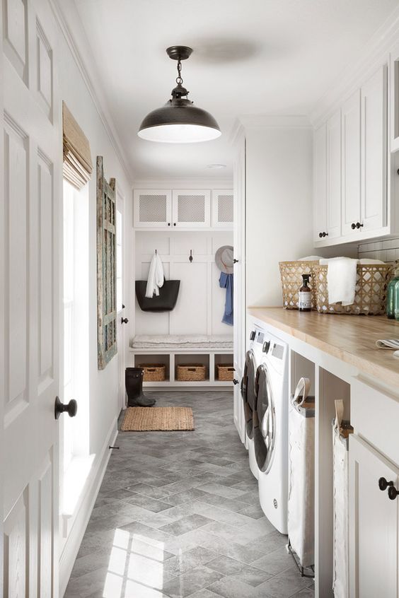 a neutral mudroom laundry with shaker cabinets, butcherblock countertops, a washing machine and a dryer plus black fixtures