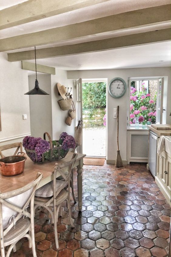 a neutral shabby chic kitchen with a Provence feel, a terracotta tile floor, shabby chic whitewashed furniture and an entrance to the garden