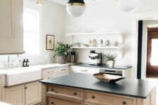 a neutral shaker style kitchen with a stained kitchen island, white and black soapstone countertops and pendant lamps on chain