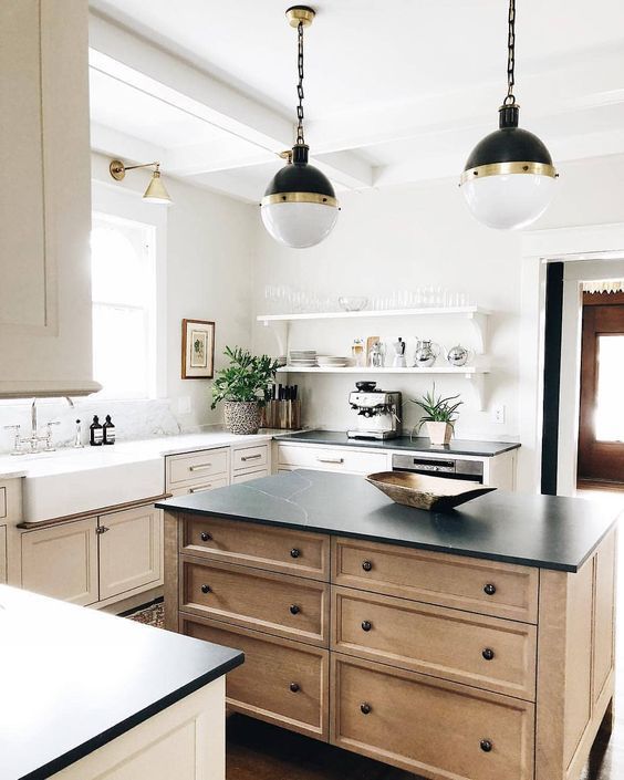 a neutral shaker style kitchen with a stained kitchen island, white and black soapstone countertops and pendant lamps on chain
