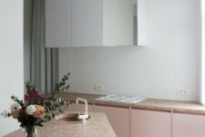 a pink and white kitchen with pretty pink terrazzo countertops and a geometric kitchen island plus black stools
