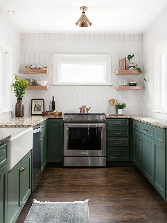 a pretty green kitchen with shaker cabinets, a white tile backsplash, open shelves and beige granite countertops