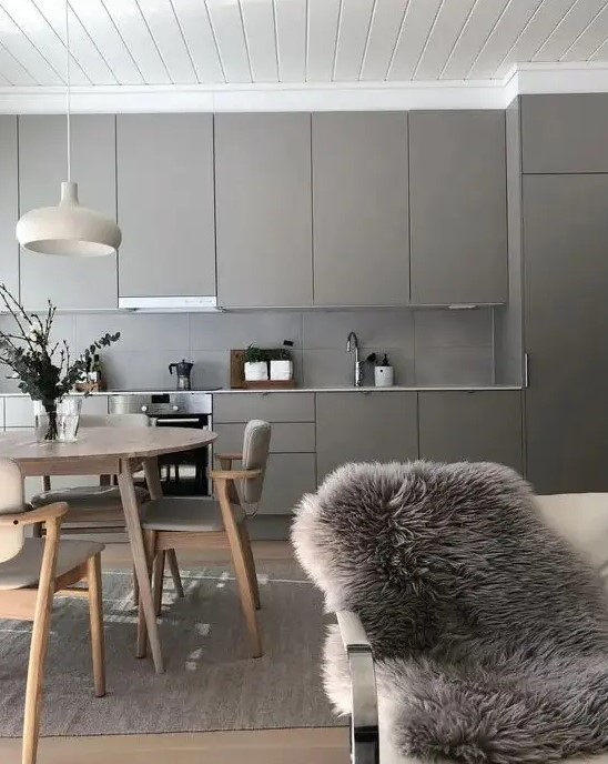 a pretty greige kitchen with sleek cabinets and a concrete tile backsplash, a neutral and cozy dining space here