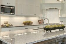 a pretty white kitchen with shaker cabinets, a white subway tile backsplash, a stained kitchen island and grey granite countertops