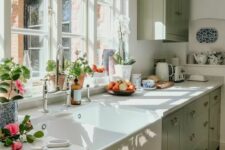 a sage green farmhouse kitchen with white stone countertops, a single upper cabinet, vintage fixtures and a vintage sink