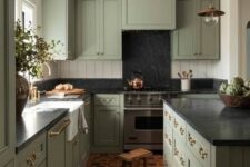 a sage green kitchen with black stone countertops and a beadboard backsplash plus terracotta tiles