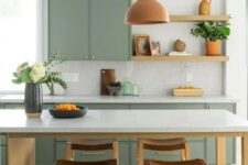 a sage green kitchen with open shelves and only lower cabinets, a kitchen island that doubles as a dining table