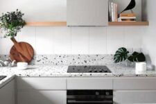 a serene Nordic kitchen with light grey cabinets and matching grey terrazzo countertops and a long open shelf instead of uppers