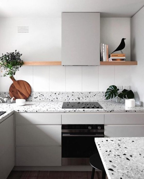 a serene Nordic kitchen with light grey cabinets and matching grey terrazzo countertops and a long open shelf instead of uppers