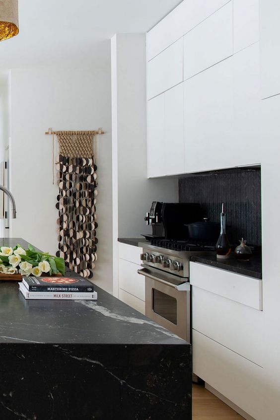 a sleek white kitchen with black soapstone countertops and a black tile backsplash is a stylish and dramatic space