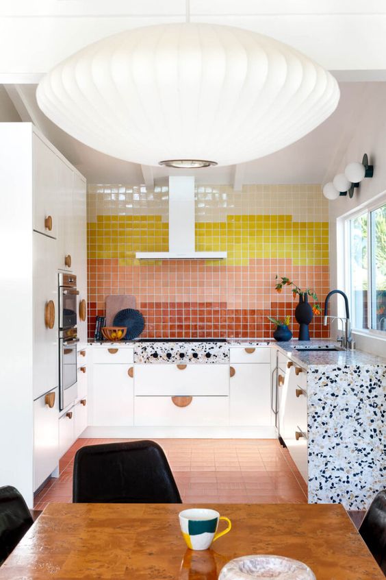 a small and super bright kitchen with flat panel cabinets, a colorful color block backsplash, white terrazzo countertops