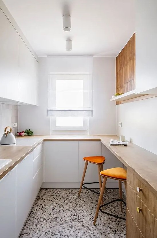 a small minimalist kitchen with sleek white cabinetry, butcherblock countertops and a bar counter for cooking and eating