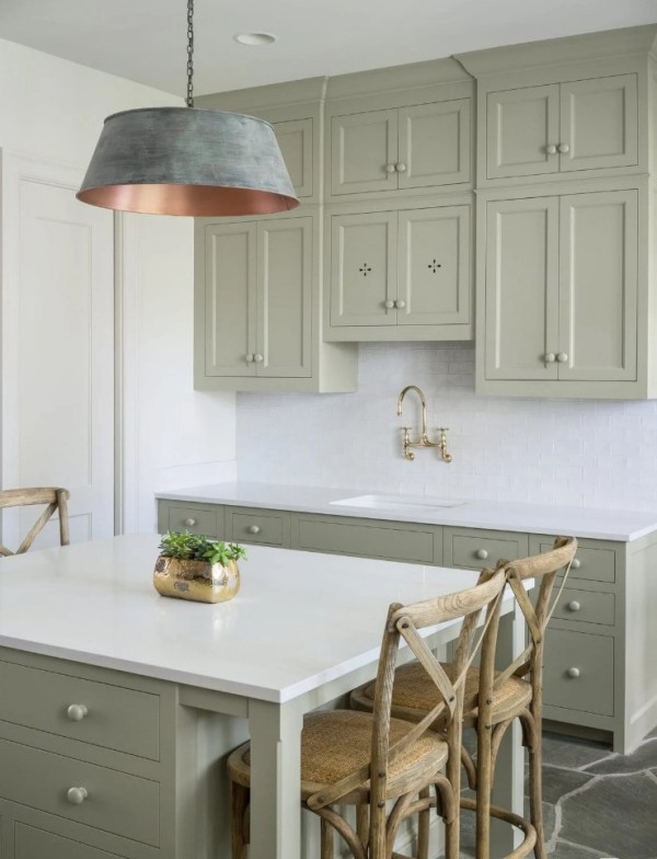 a small sage green kitchen with shaker and flat panel cabinets, a white subway tile backsplash and white countertops plus a catchy brushed lamp