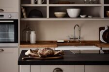 a sophisticated greige kitchen with shaker cabinets, open box shelves, butcherblock and soapstone countertops