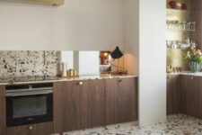 a stylish contemporary kitchen with stained lower cabinets, a terrazzo backsplash and countertops and a matching floor