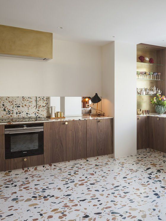 a stylish contemporary kitchen with stained lower cabinets, a terrazzo backsplash and countertops and a matching floor