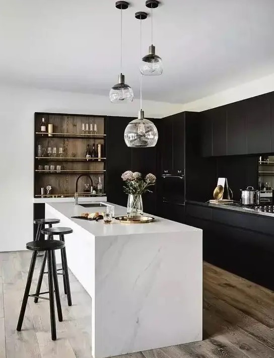 a stylish contrasting kitchen with sleek black cabinets, a white stone kitchen island, built-in shelves and a cluster of pendant lamps