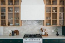 a stylish kitchen with dark green and stained kitchen cabinets, arches and glass ones, with a glossy tile backsplash and a white hood
