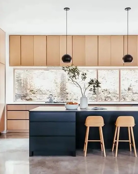 a stylish light stained kitchen with a large window backsplash, a navy kitchen island, black pendant lamps and tall stained stools is perfection