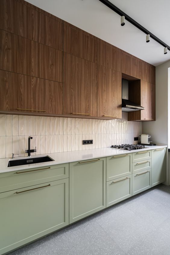 a two-tone kitchen with timber and sage green cabinets, a white skinny tile backsplash and white countertops plus black fixtures