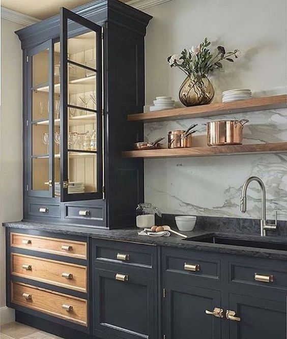 a vintage black kitchen with shaker and glass front cabinets, black soapstone countertops and stained open shelves