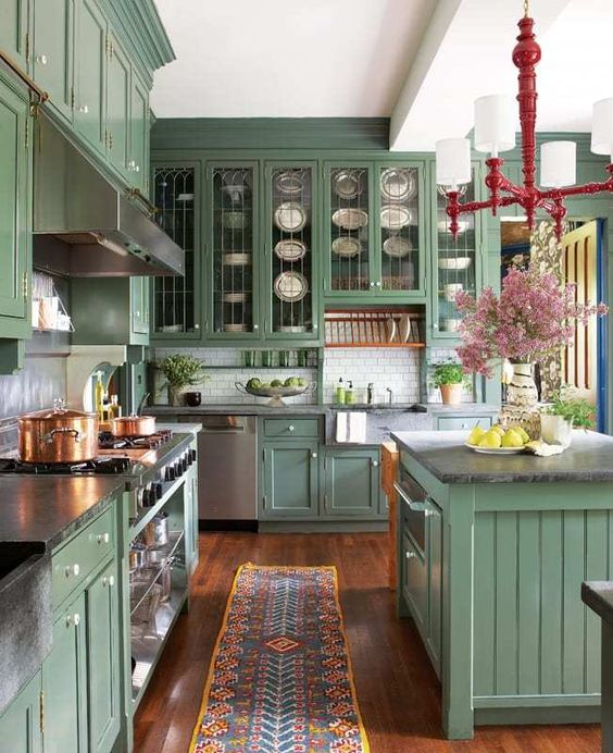 a vintage-inspired green kitchen with inlay and glass cabinets, a white subway tile backsplash, black stone countertops