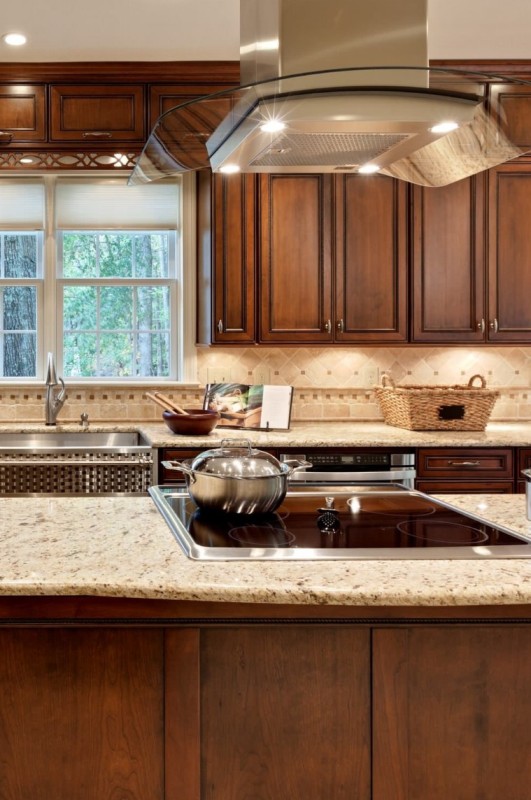 a vintage rich-stained kitchen with shaker cabinets, a tan and beige tile backsplash and matching granite countertops