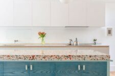 a vivacious kitchen with white sleek cabinets, a colorful kitchen island with a bright terrazzo countertop and pendant lamps