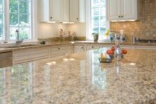 a welcoming kitchen with creamy shaker cabinets, a stained kitchen island, a beige tile backsplash and tan granite countertops