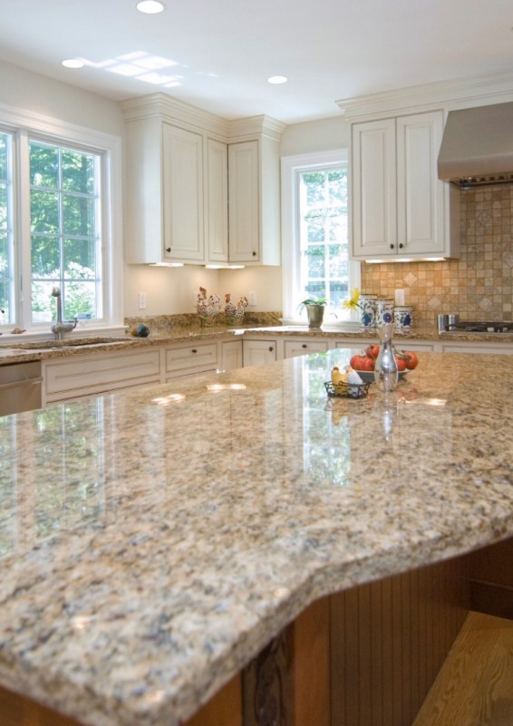 a welcoming kitchen with creamy shaker cabinets, a stained kitchen island, a beige tile backsplash and tan granite countertops