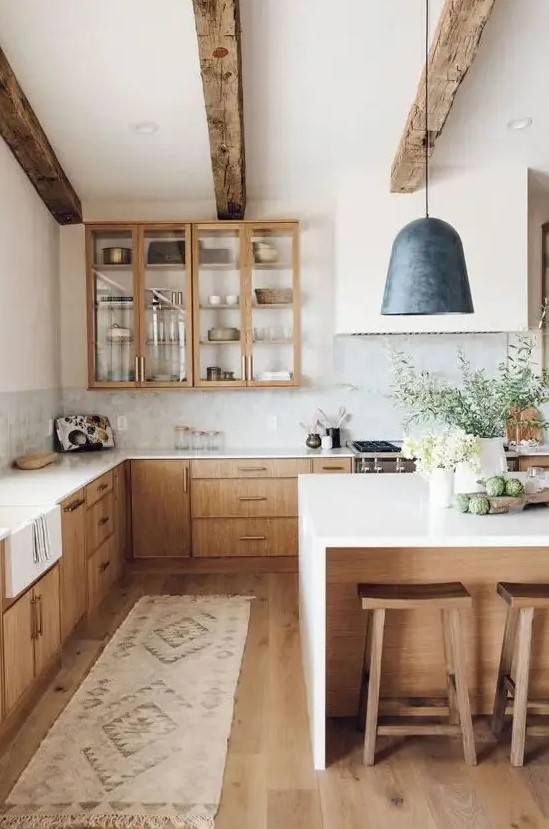 a welcoming modern farmhouse kitchen with light-stained cabinets, wooden beams and stools that warm up the space