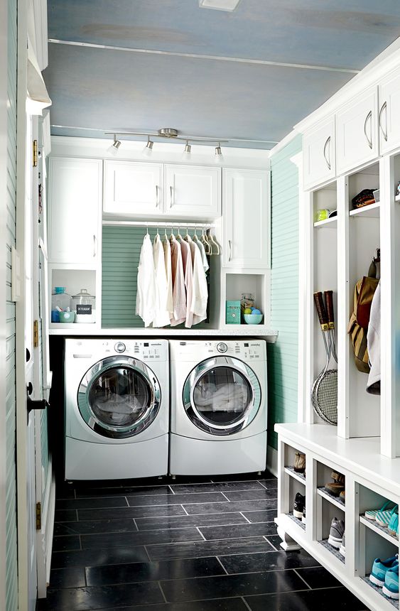 a white and mint-colored mudroom laundry with shaker cabinets, a mint green accent wall, an open storage unit and a washing machine and a dryer