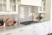 a white kitchen with shaker style cabinets, a grey tile backsplash, grey granite countertops and built-in appliances